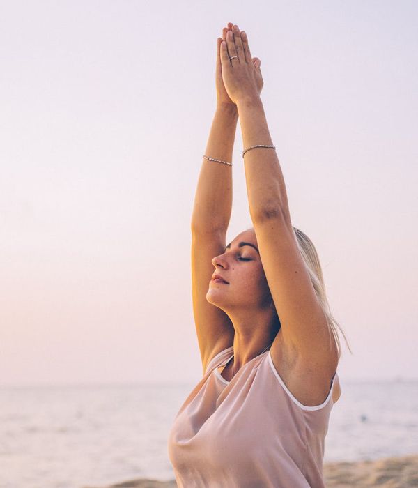 Person feeling energized and stretching outdoors at sunrise.